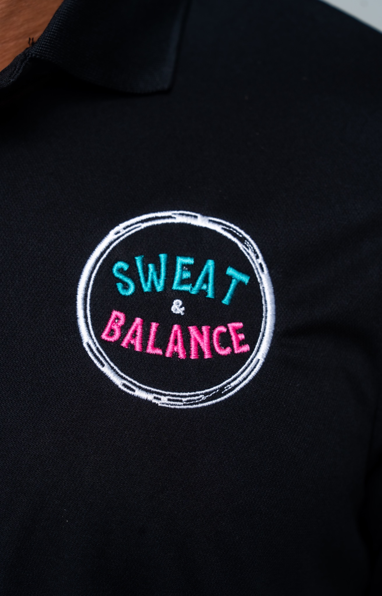 Sweat and Balance embroidered logo on black polo